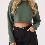 A woman wearing a stylish womens cropped green jumper in a front view.