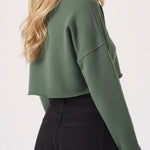 Side view of a model in the womens cropped green jumper showing the raw hem.
