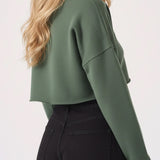 Side view of a model in the womens cropped green jumper showing the raw hem.