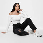 Model seated on the floor showcasing knee rips in Women's Distressed Black Wash Straight Jeans