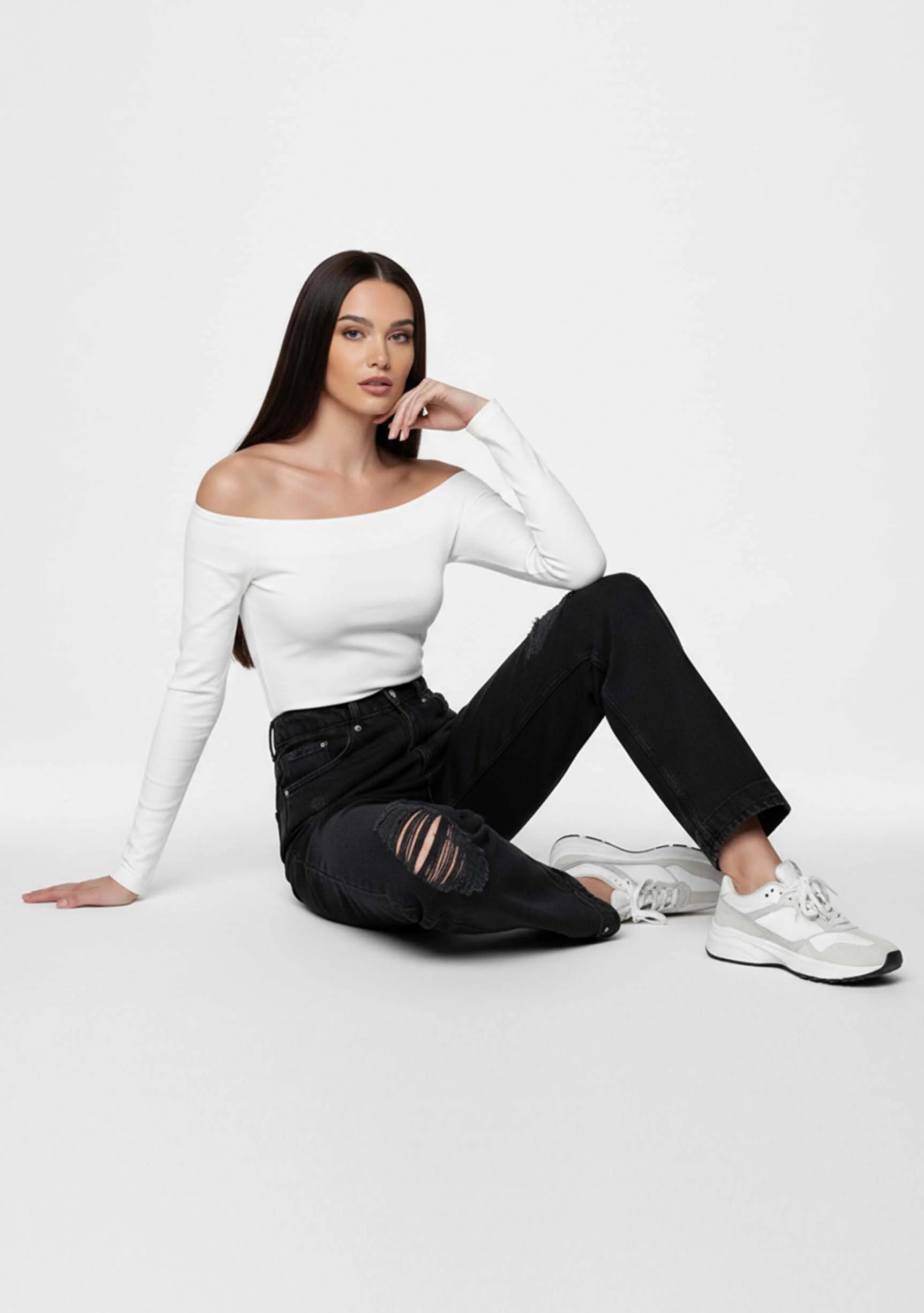 Model seated on the floor showcasing knee rips in Women's Distressed Black Wash Straight Jeans