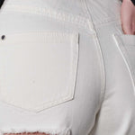 Detailed view of the rip and distressing under the back pocket of the jeans.