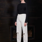 Side profile of a model wearing the off-white distressed tapered jeans.