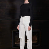 Side profile of a model wearing the off-white distressed tapered jeans.