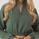 Close up view of the elasticated hem and zip on a dark green sweatshirt for women