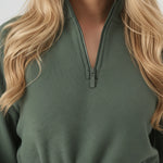 Detailed front shot of the high neck collar and zipper on a green sweatshirt