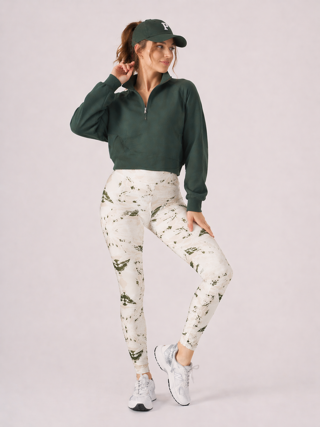 A woman wearing womens-green-stone-print-high-waist-leggings styled with a green half zip crop sweatshirt and white trainers, front view
