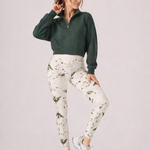 A woman wearing womens-green-stone-print-high-waist-leggings styled with a green half zip crop sweatshirt and white trainers, front view