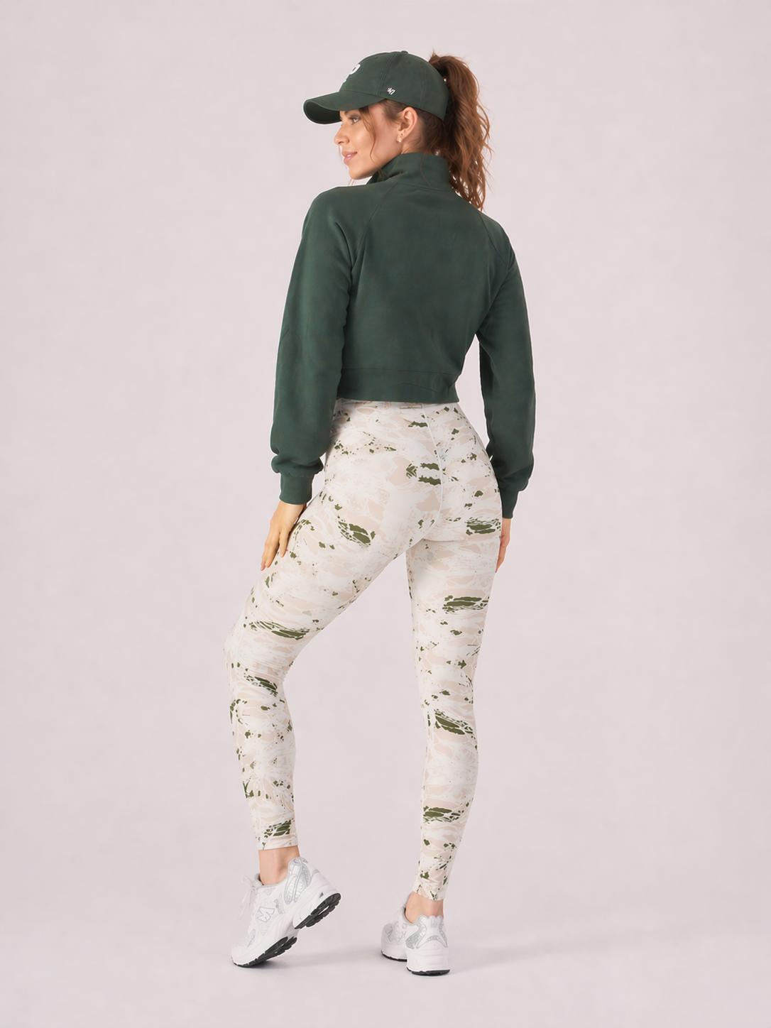 A woman wearing womens-green-stone-print-high-waist-leggings back view showing the wide dipped waistband and full length fit