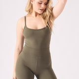 Close up front view of a woman wearing a green unitard and holding the neckline