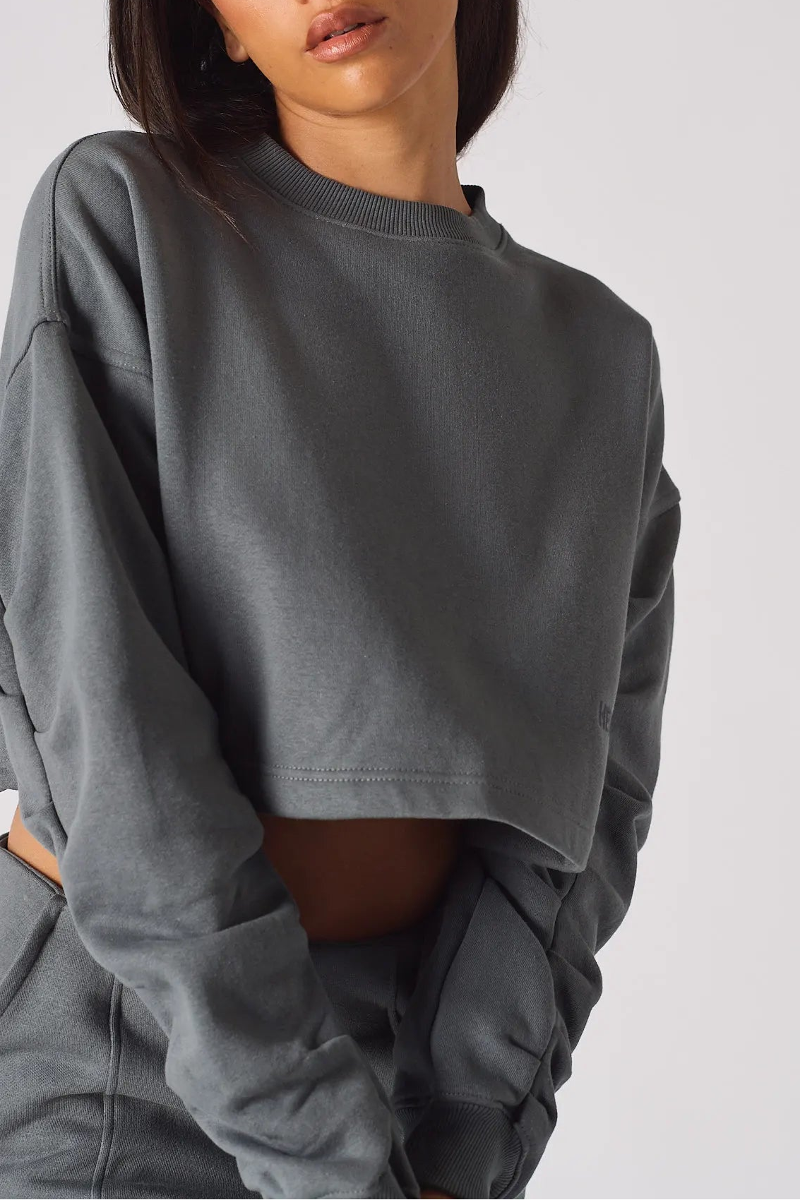 A close up shot of the cropped hem and fabric on a grey crew neck jumper