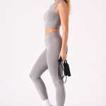 A woman wearing womens-grey-high-waist-leggings side view showing the deep waistband and full length fit, holding a skipping rope