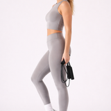 A woman wearing womens-grey-high-waist-leggings side view showing the deep waistband and full length fit, holding a skipping rope