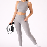 A woman wearing womens-grey-high-waist-butt-lifting-leggings holding a skipping rope, front view styled with a matching grey crop top and cream cap