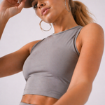 A woman wearing womens-grey-racerback-training-crop-top in a dynamic movement pose showing the stretch and fit