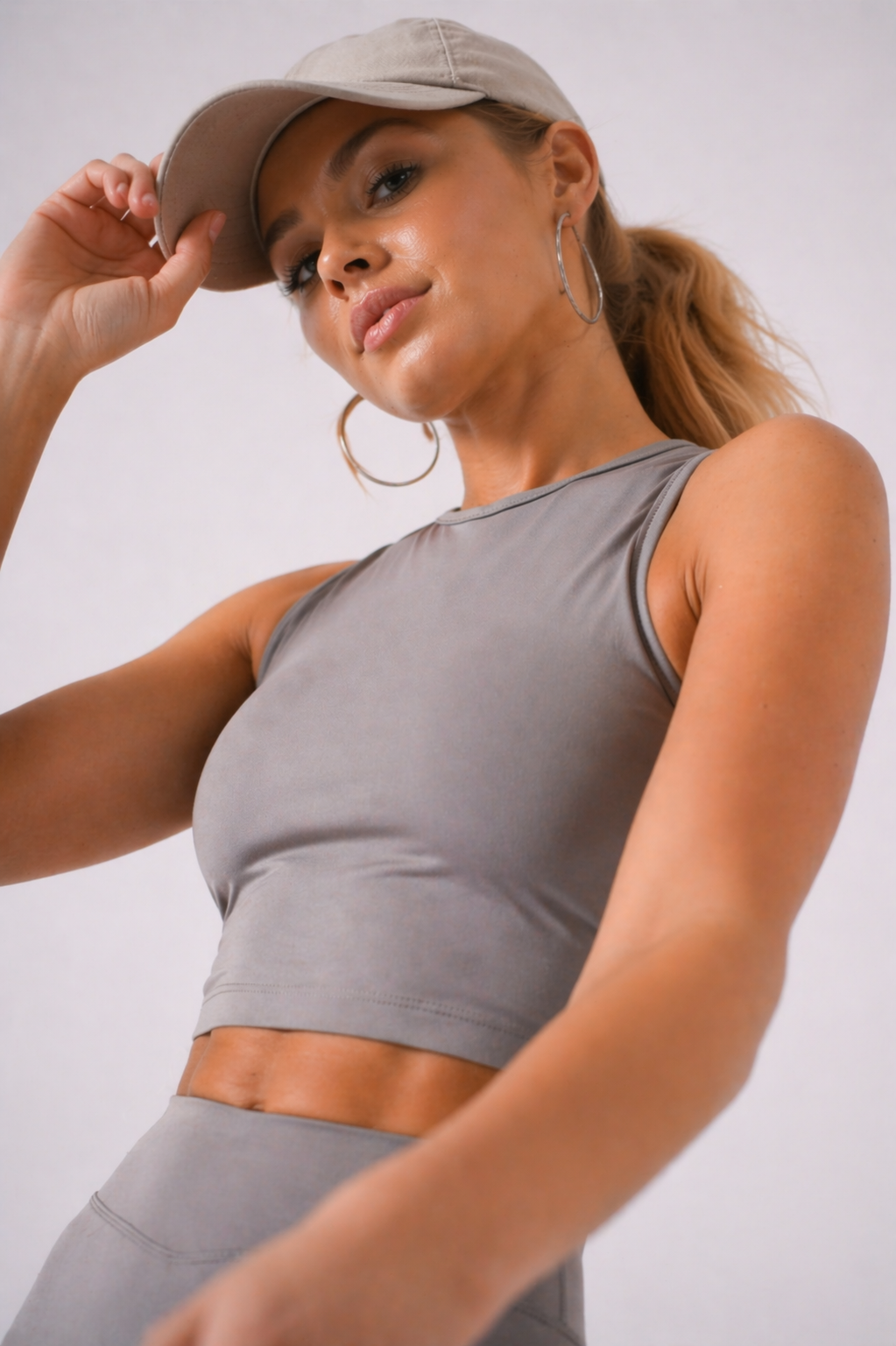 A woman wearing womens-grey-racerback-training-crop-top in a dynamic movement pose showing the stretch and fit