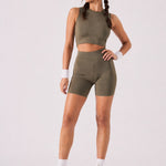 A woman wearing womens-khaki-high-waist-biker-shorts full length front view styled with a matching khaki crop top and olive trainers