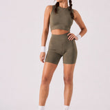 A woman wearing womens-khaki-high-waist-biker-shorts full length front view styled with a matching khaki crop top and olive trainers