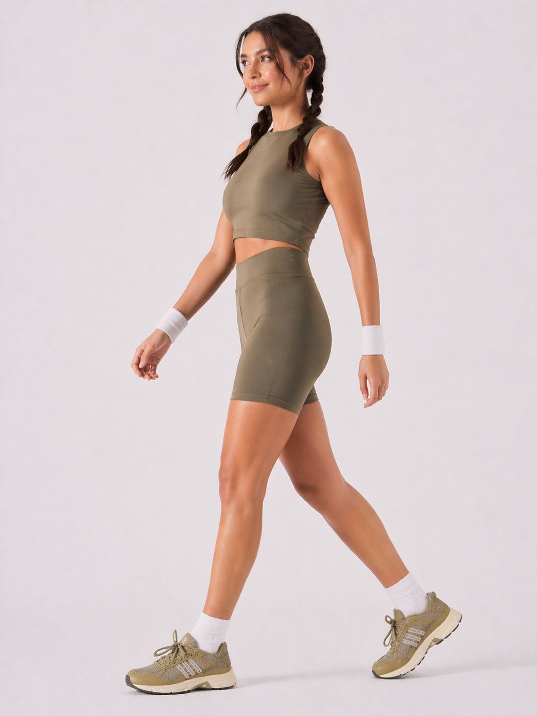 A woman wearing womens-khaki-high-waist-biker-shorts walking side view showing the mid thigh length and fitted cut
