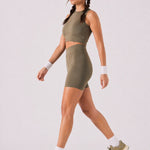 A woman wearing womens-khaki-high-waist-biker-shorts walking side view showing the mid thigh length and fitted cut