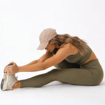 A woman seated in a forward fold wearing womens-khaki-high-waist-leggings showing comfort and flexibility during stretching