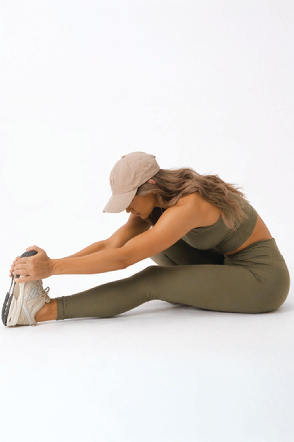 A woman seated in a forward fold wearing womens-khaki-high-waist-leggings showing comfort and flexibility during stretching