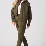 A woman standing in a complete khaki tracksuit set with white trainers