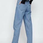 Front full view of a model standing straight in women's light wash straight fit trousers with studded accents.