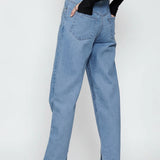 Front full view of a model standing straight in women's light wash straight fit trousers with studded accents.