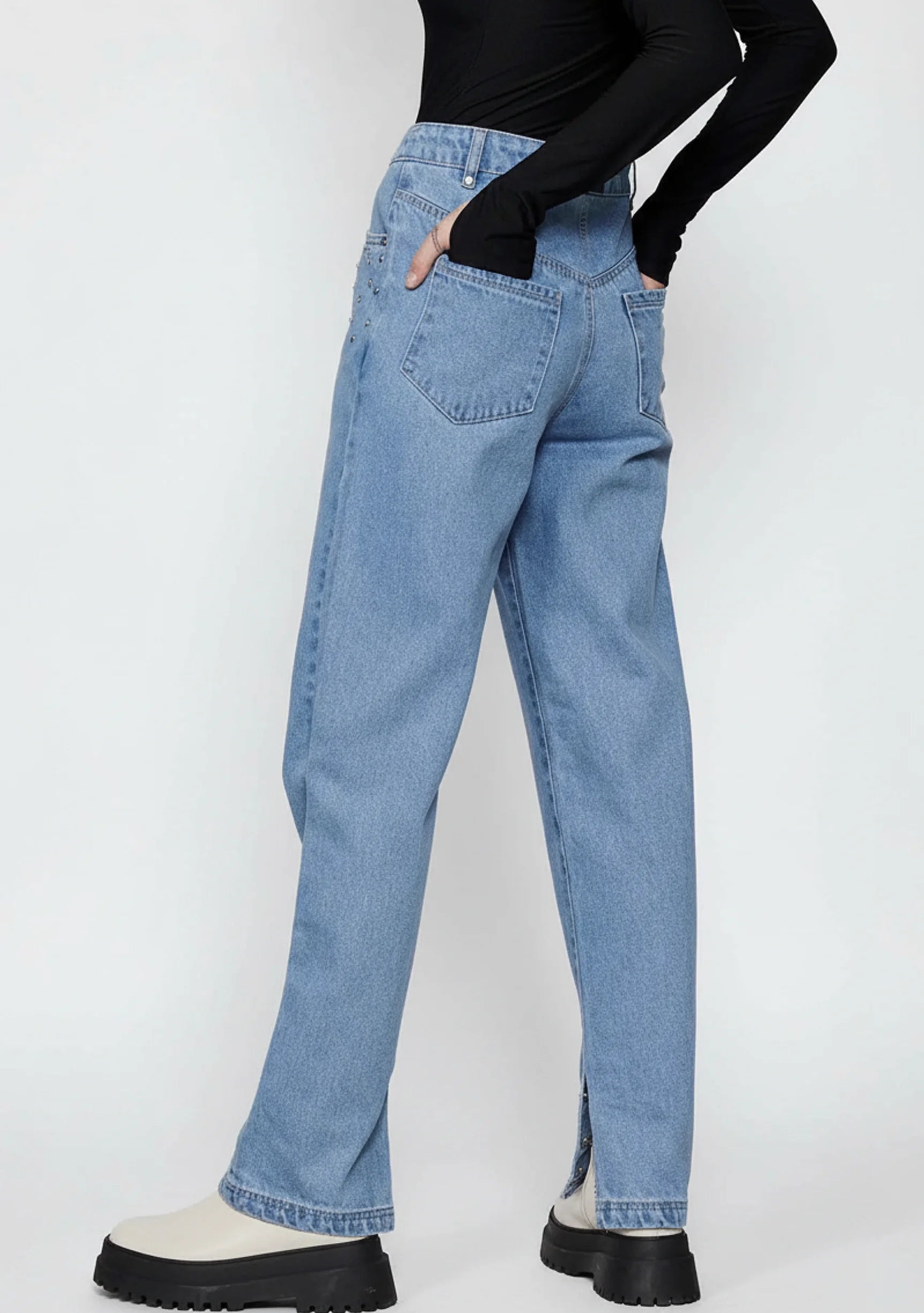 Front full view of a model standing straight in women's light wash straight fit trousers with studded accents.