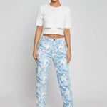 Front full view of women's marble print straight leg jeans featuring a light blue abstract wash and slit hems.