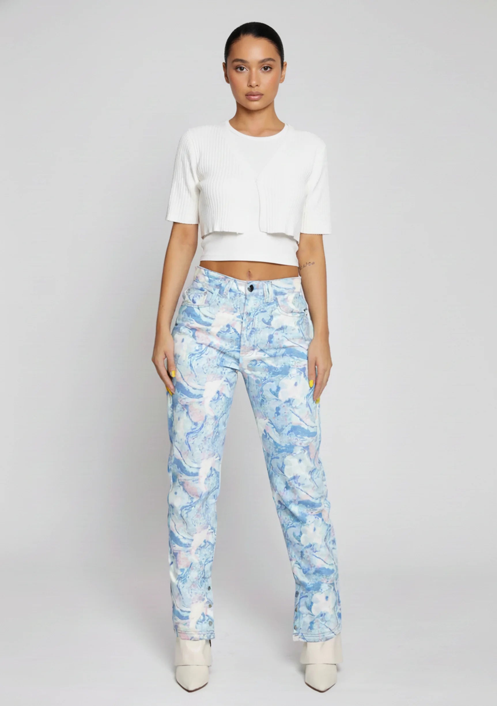 Front full view of women's marble print straight leg jeans featuring a light blue abstract wash and slit hems.