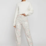 Front full view of women's pastel marble print tapered jeans paired with a cropped white sweater.