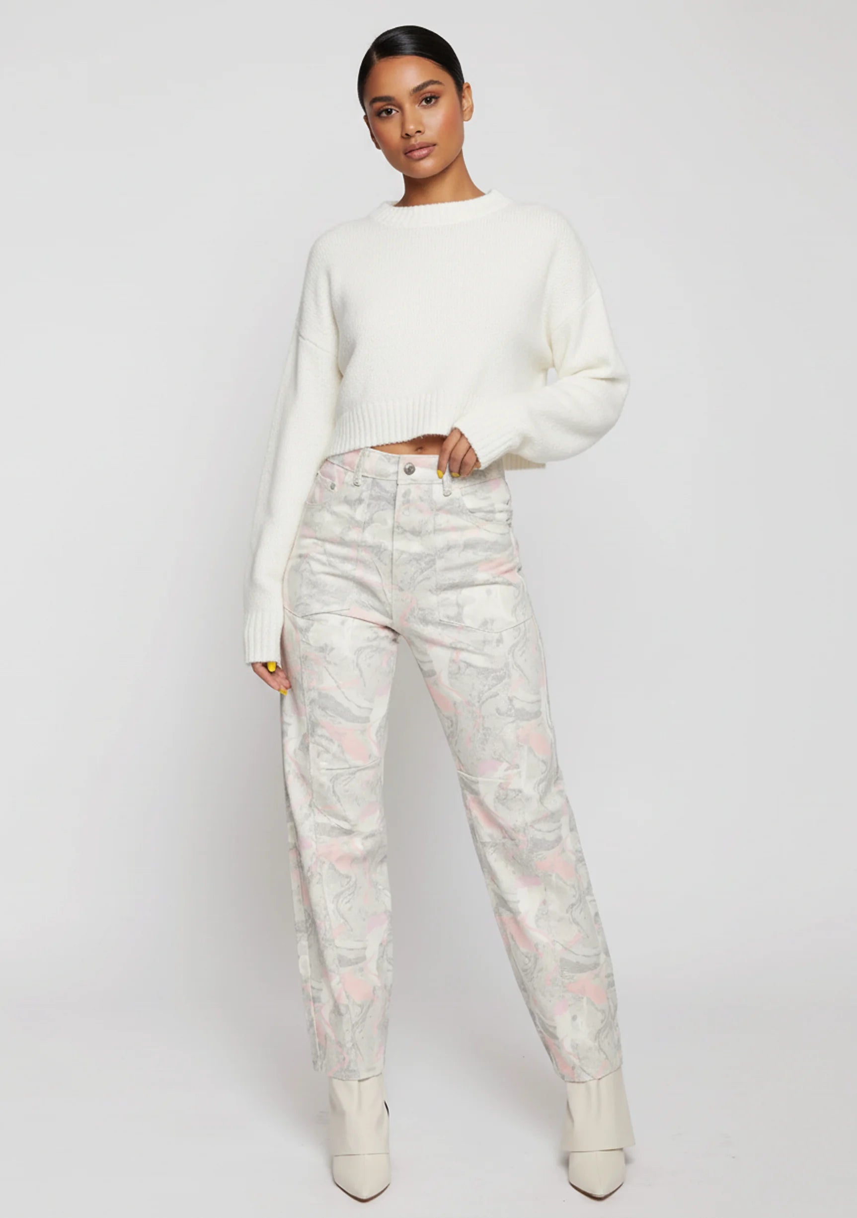 Front full view of women's pastel marble print tapered jeans paired with a cropped white sweater.