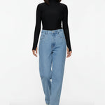 Front walking pose of a model wearing women's vintage wash denim pants featuring metallic pocket studs.