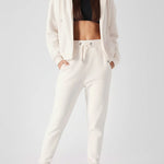 Full length shot of a model wearing womens white zip up hoodies and matching joggers.