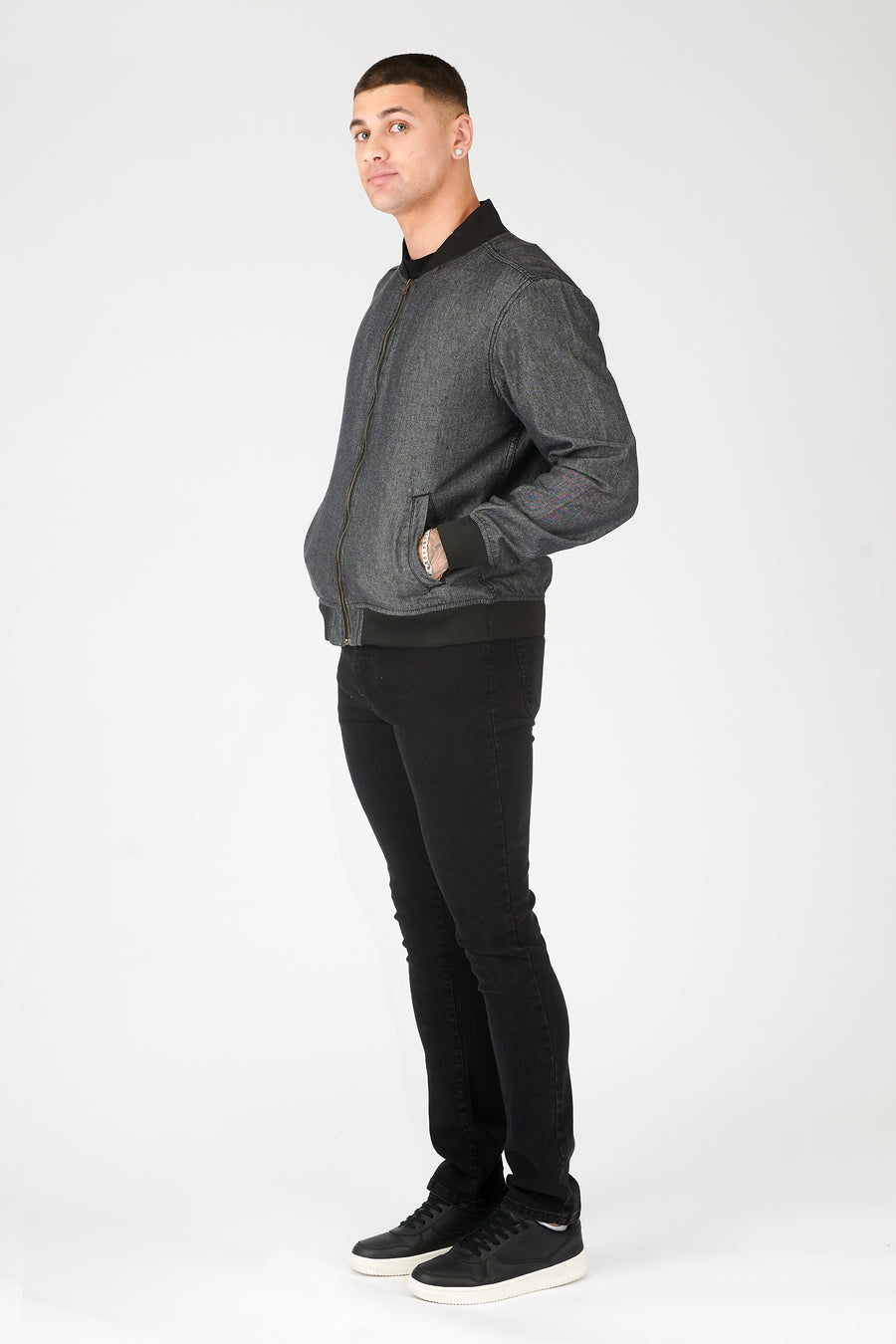 Full body on side shot of a standing male model wearing a zipped up JMOJO Grey Bomber Jacket