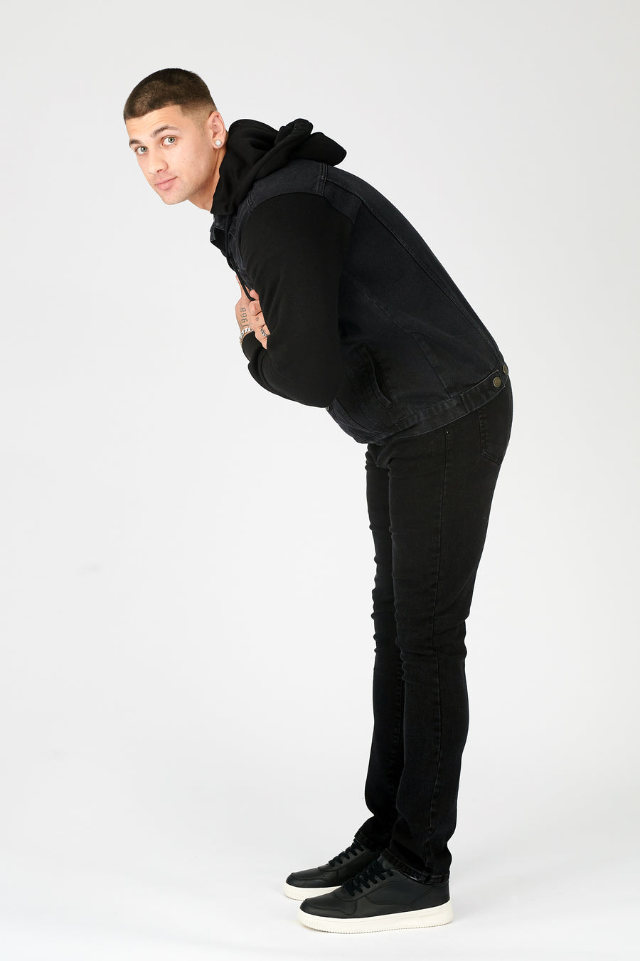 Full body leaning style shot of a standing male model wearing a JMOJO Black Wash Hooded Fleece Denim Jacket