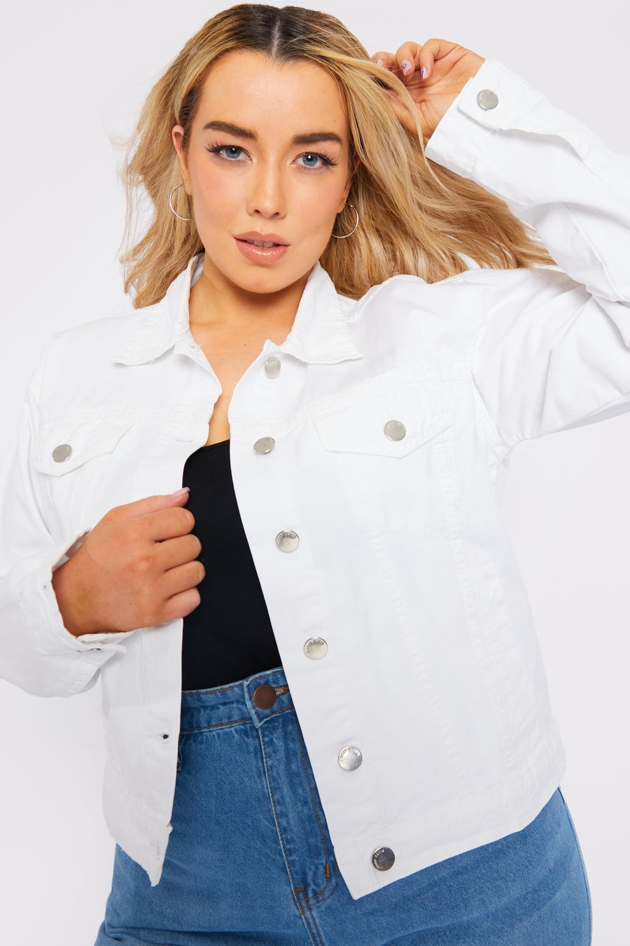 Body shot of a standing plus size female model wearing a JMOJO White Denim Trucker Jacket