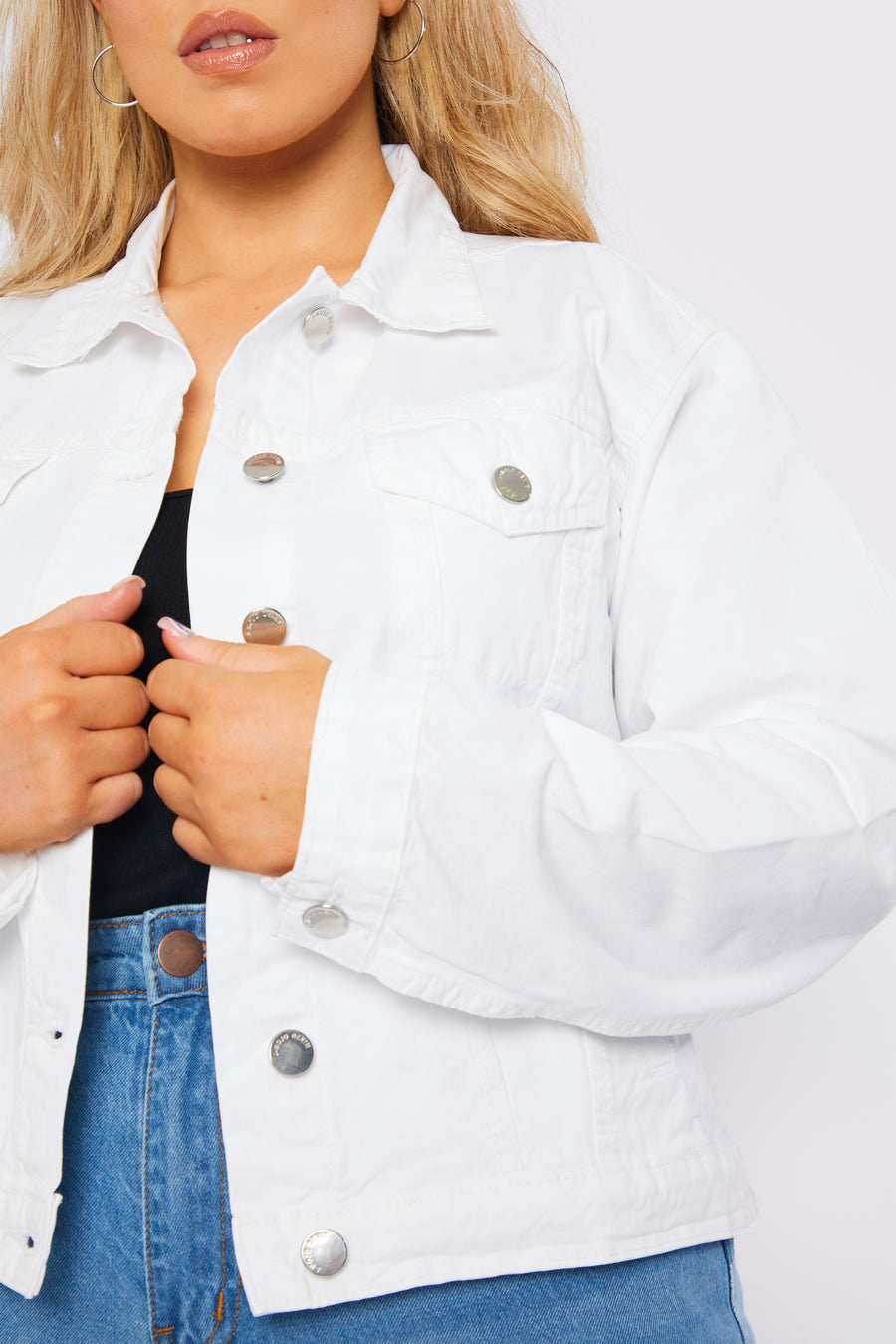 Close up product detail shot of a standing plus size female model wearing a JMOJO White Denim Trucker Jacket