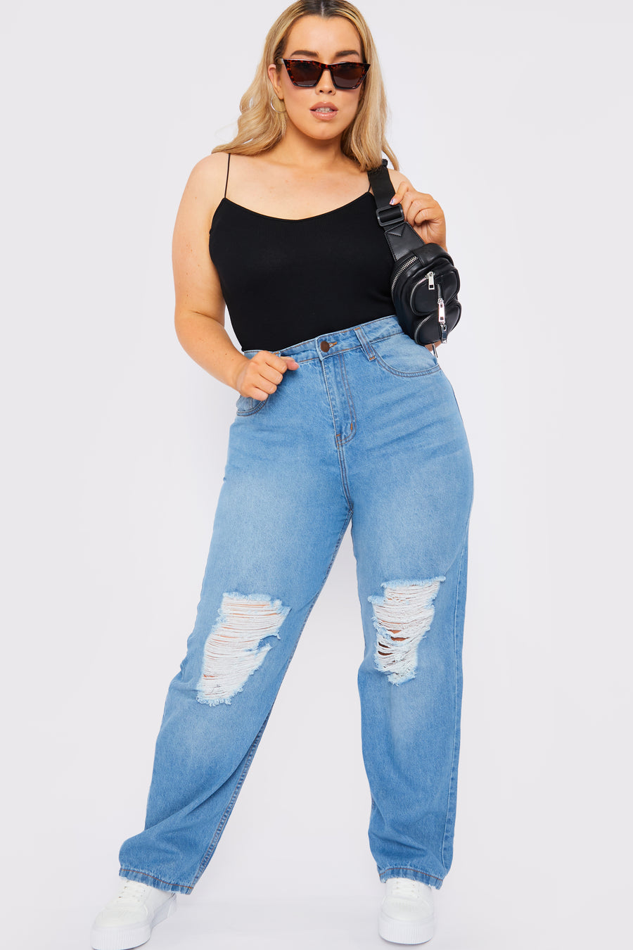 Full body style shot of a standing plus size female model wearing JMOJO Light Blue Wash High Waisted Straight Leg Ripped Jeans holding a handbag over her shoulder and wearing sunglasses