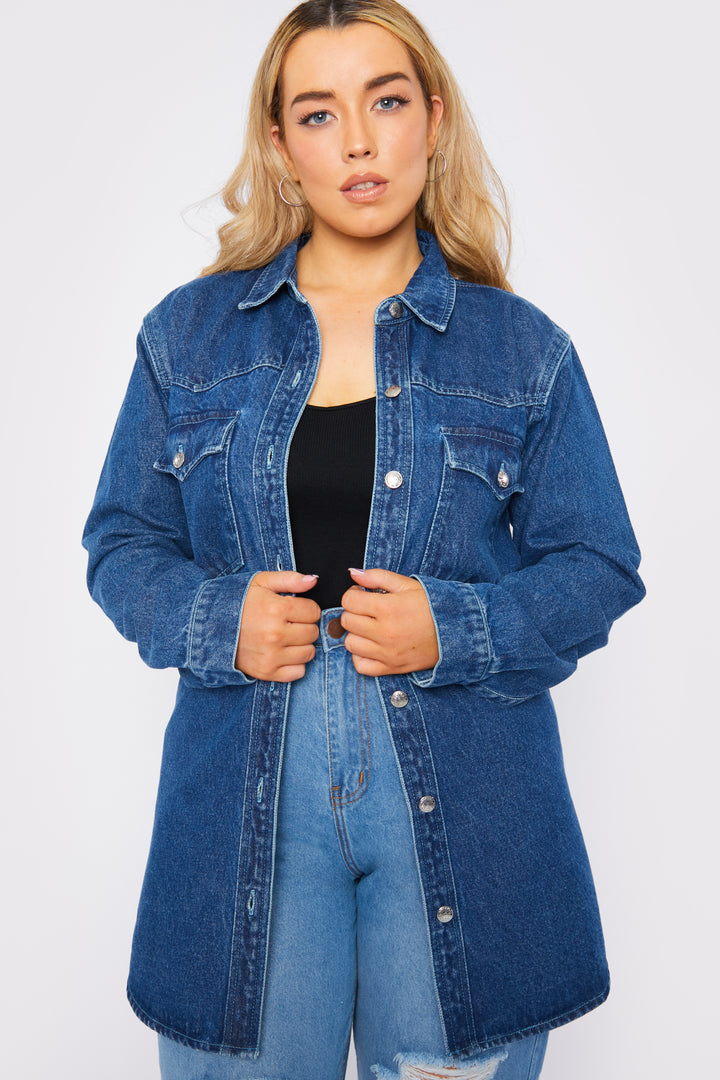 Body shot of a standing plus size female model wearing a JMOJO Mid Blue Wash Long Sleeve Denim Shirt Dress