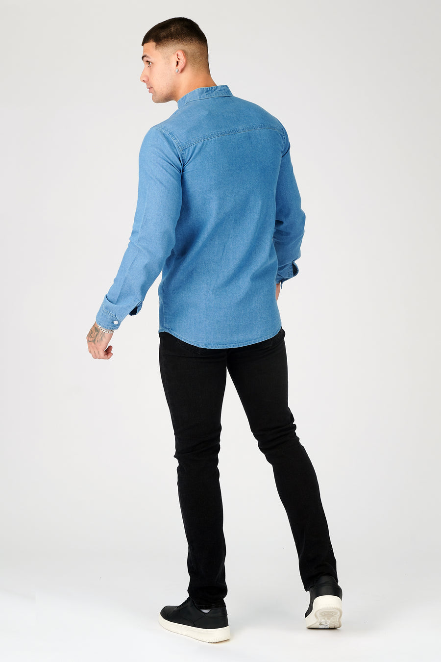 Body back shot of a standing male model wearing a JMOJO Blue Slim Fit Grandad Collar Denim Shirt