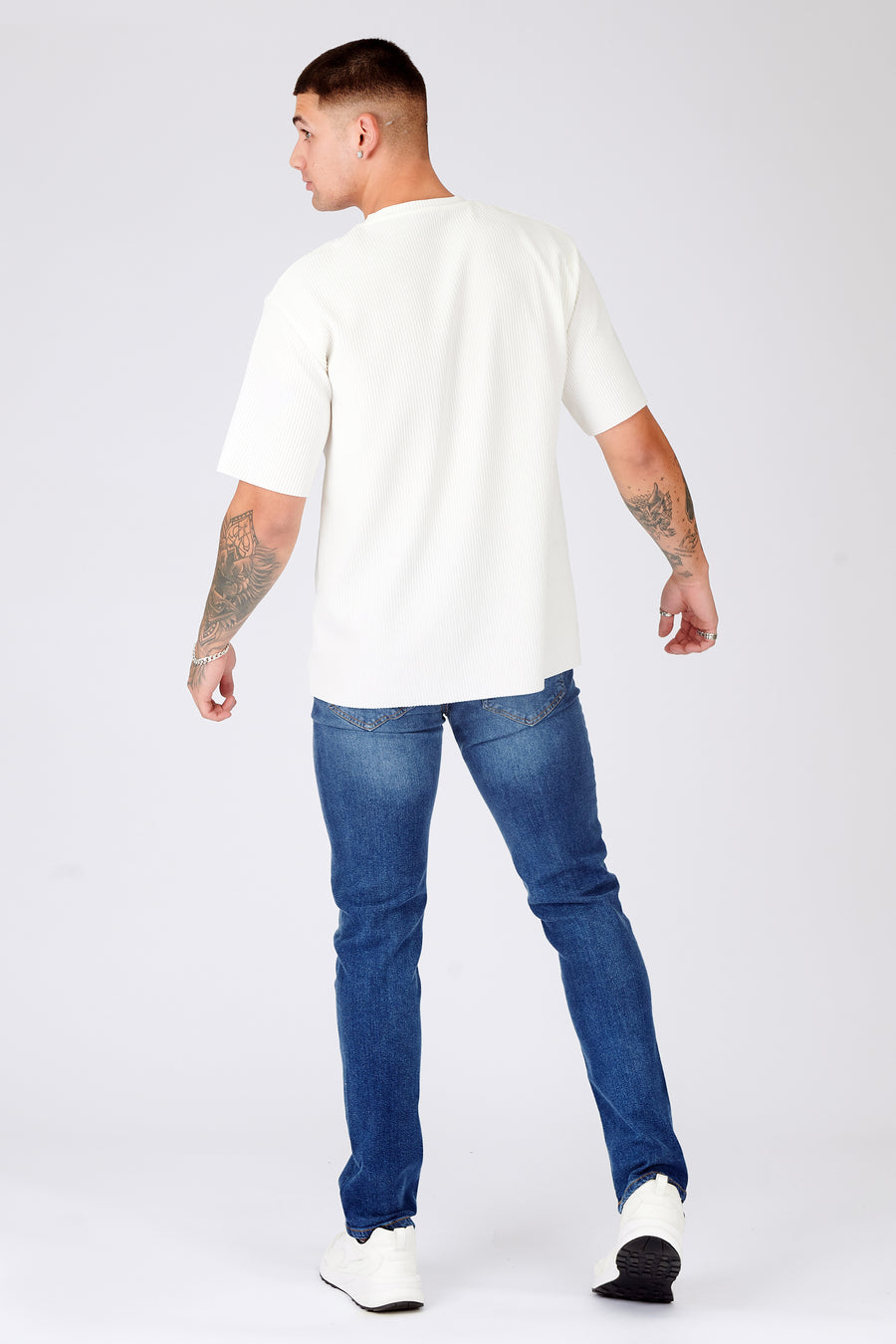 Full body back shot of a standing male model wearing JMOJO Mid Blue Wash Slim Fit Denim Jeans