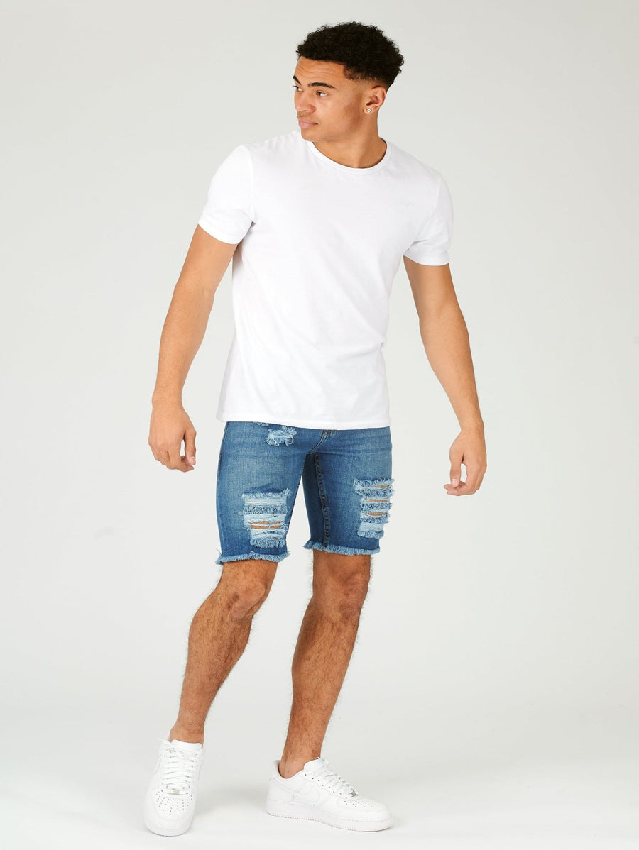 Full body shot of a standing male model wearing JMOJO Light Blue Wash Slim Fit Ripped Denim Shorts