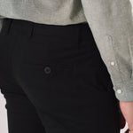 Detail shot of the back pocket on black slim fit chinos trousers.