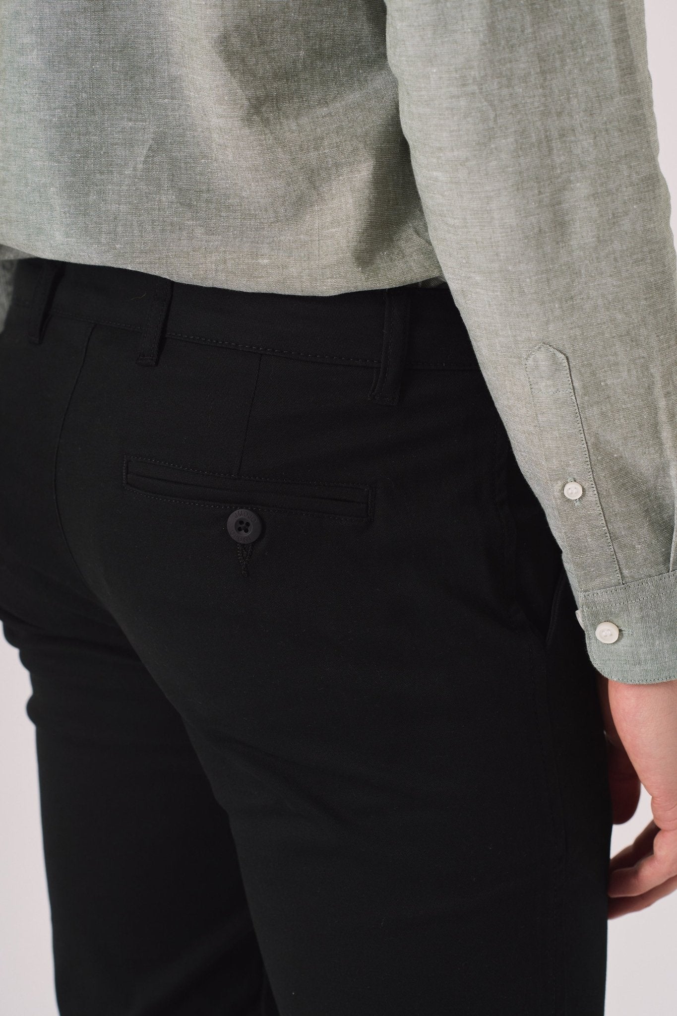 Detail shot of the back pocket on black slim fit chinos trousers.
