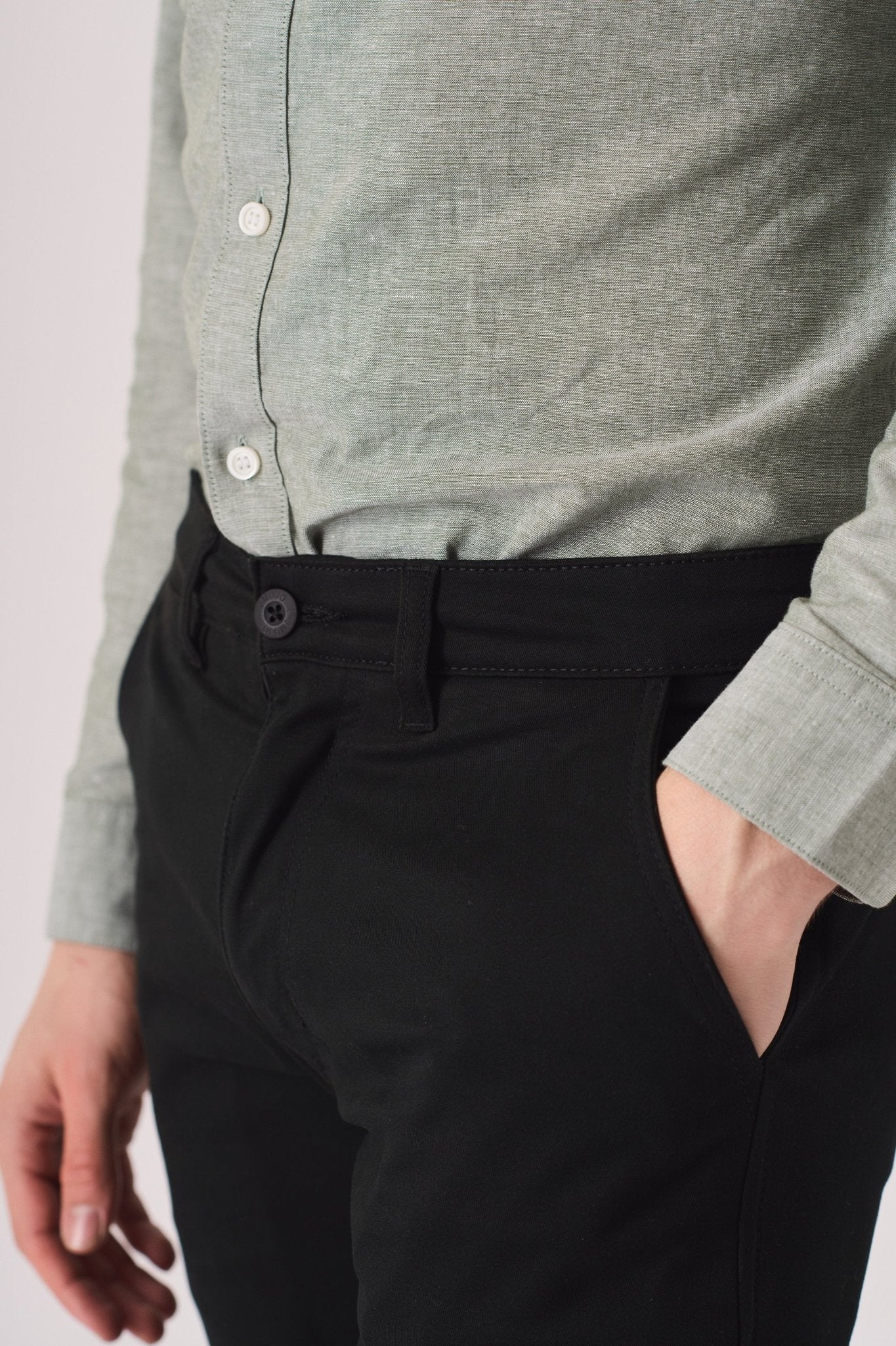 Close up of the front pocket on black slim fit chinos trousers.