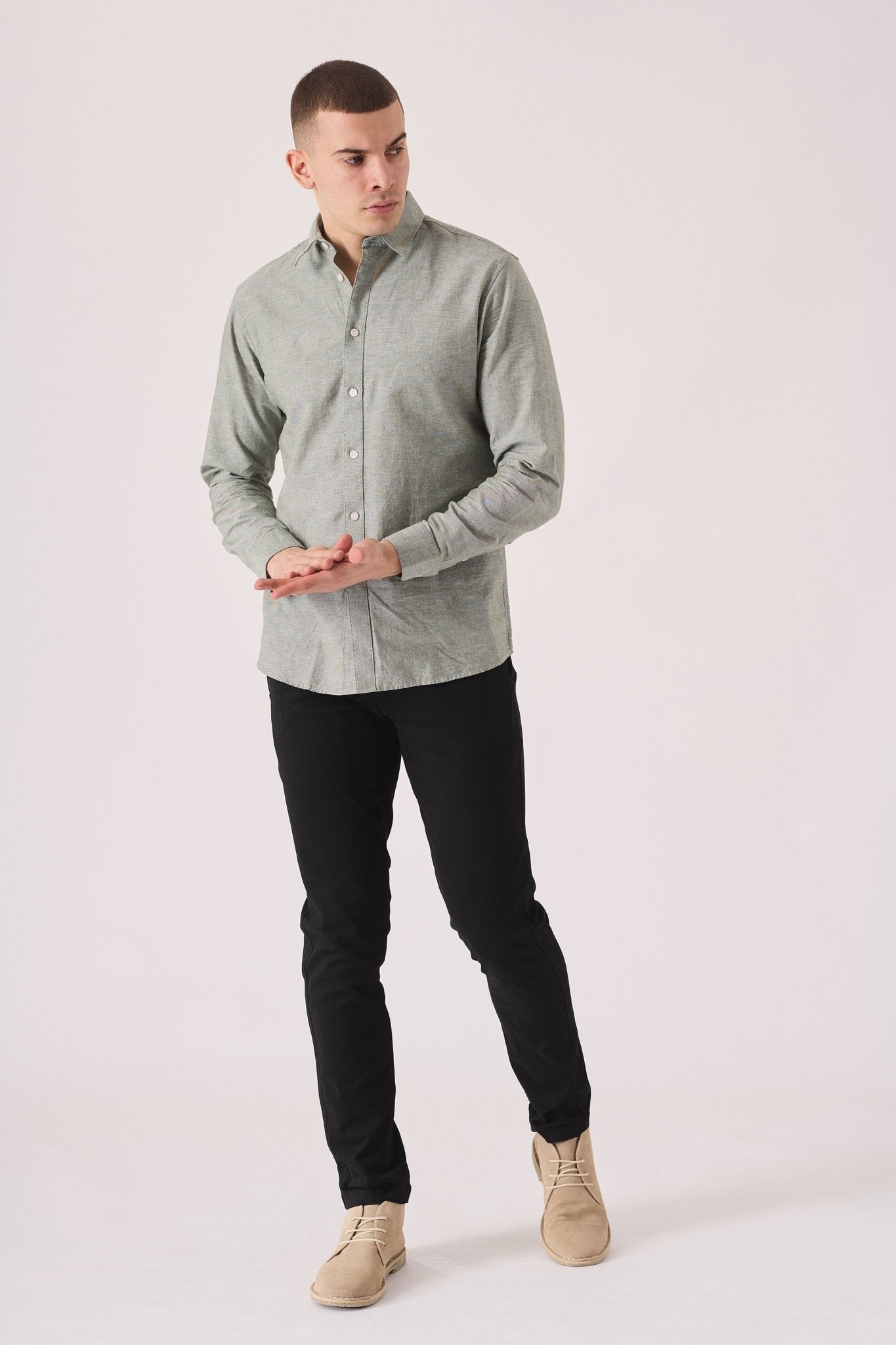 Man wearing black slim fit chinos trousers with a green shirt.