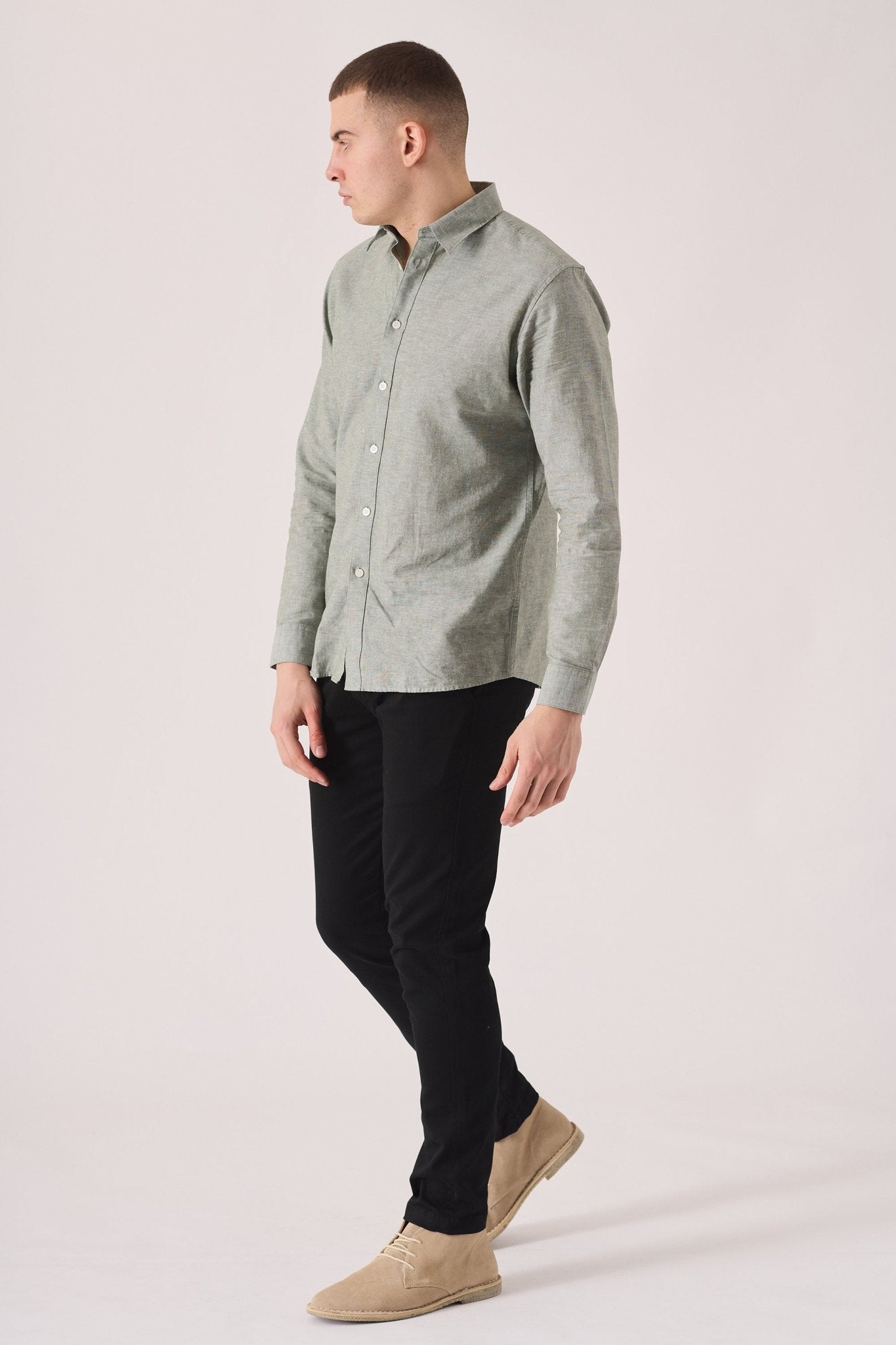 Side view of a man in black slim fit chinos trousers walking.